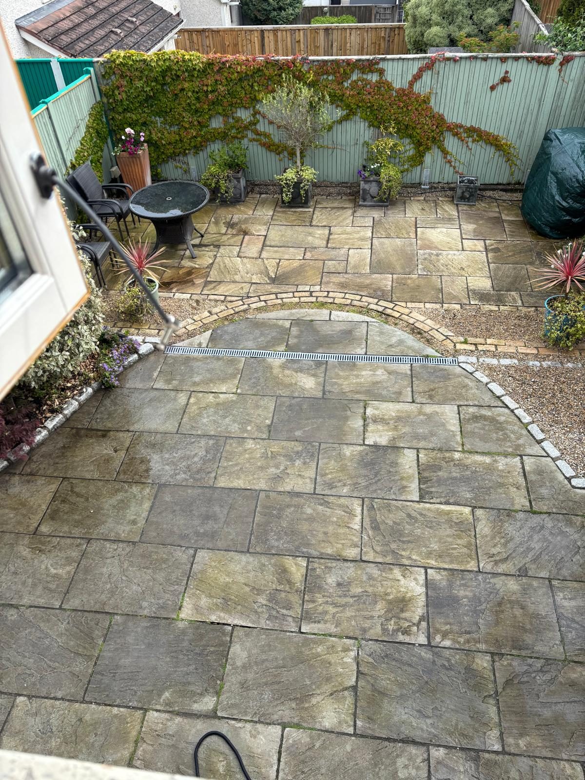 Curved sandstone patio before cleaning — algae and grime dulling the stone