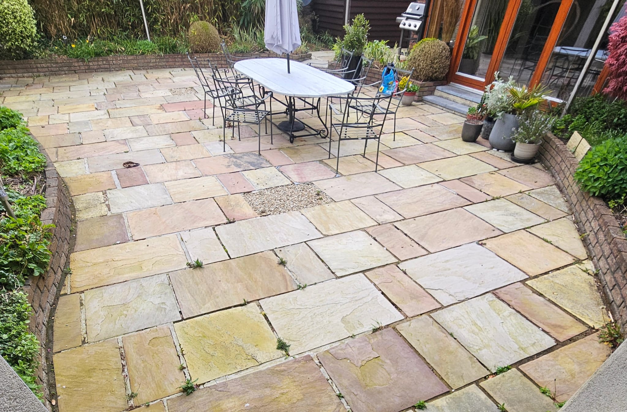 Indian sandstone patio before cleaning — weeds in the joints, dulled stone
