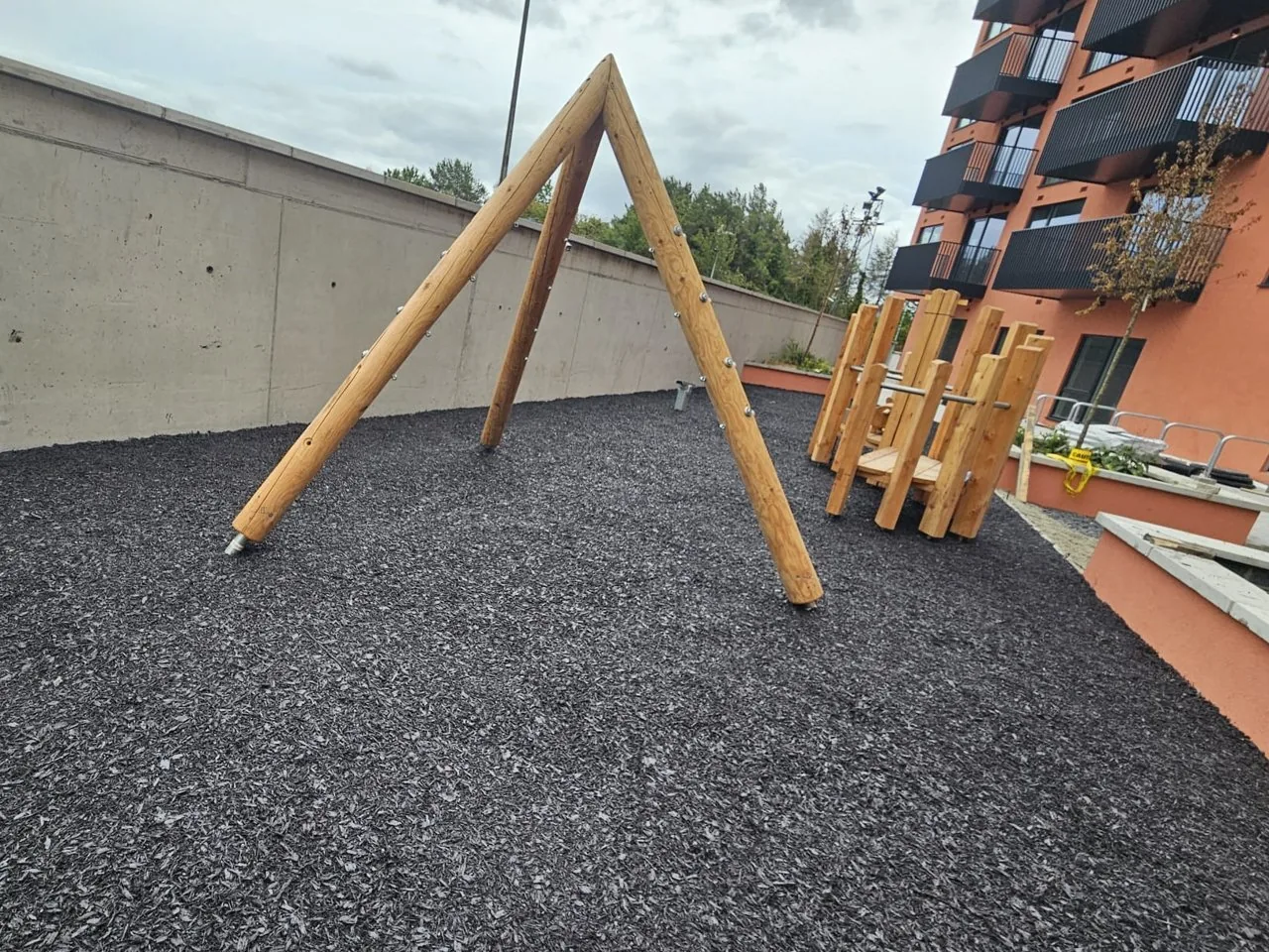 Resin bound rubber mulch laid under a new timber swing frame at an apartment complex playground in Tallaght, Dublin